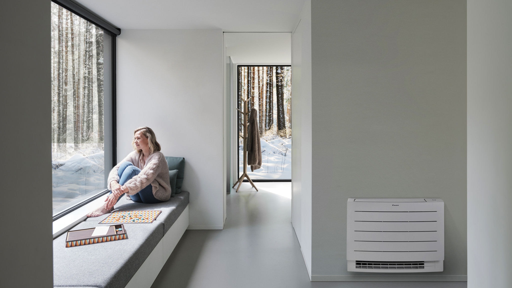 Une femme regarde le tapis de neige blanc à l'extérieur et profite d'un intérieur chauffé grâce la console carrossée Perfera.